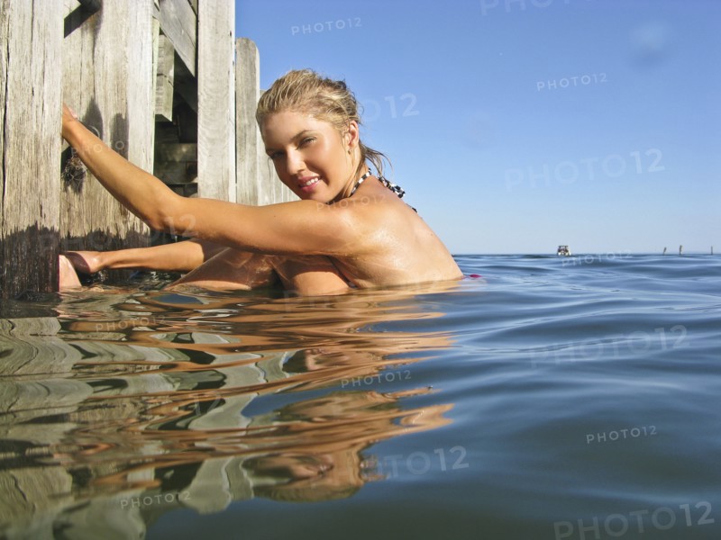 Young Woman in Water Holding on to Pier Steps, Portrait