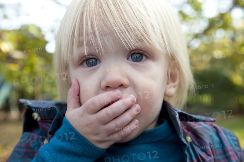 Young Blonde Boy With Hand Over Mouth