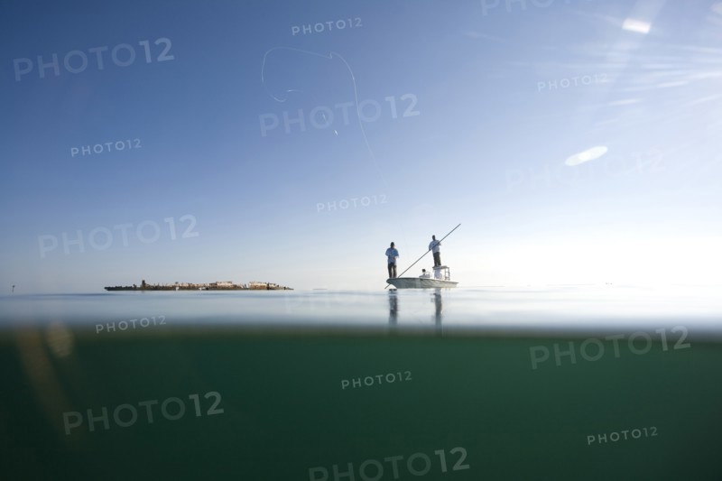 Over and Underwater View of Two Men Fly Fishing in Boat Near Shipwreck, Florida Keys, USA