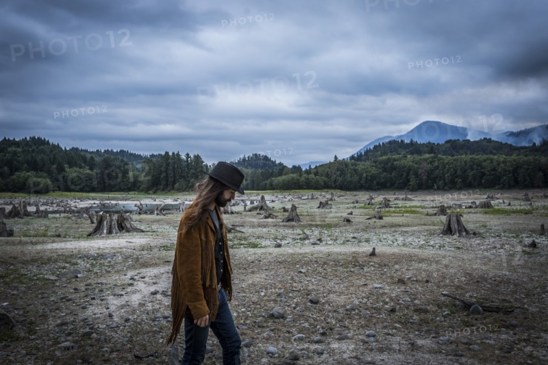 Young Adult Man Walking Across Dried Up Lake with Wildfire Smoke in Background
