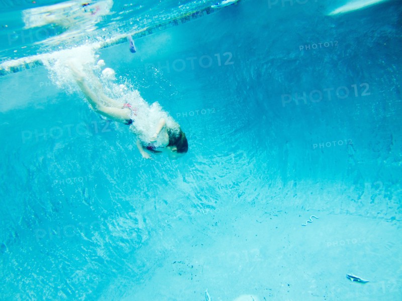 Girl Swimming Underwater after Pool Toy