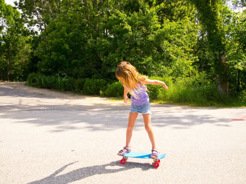 Young Girl Riding Skateboard in Street