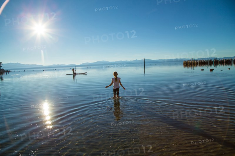 Young Girl Wading out to Woman on Paddle Board, Lake Tahoe, Nevada, USA