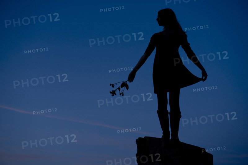 Girl Standing on Rock Holding Flowers, Silhouette
