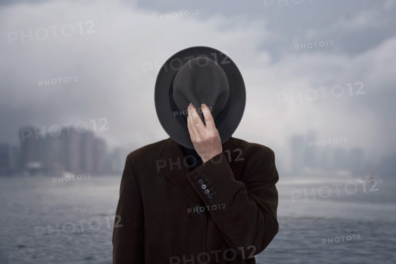 Man with Hat Covering his Face against Cloudy Sky