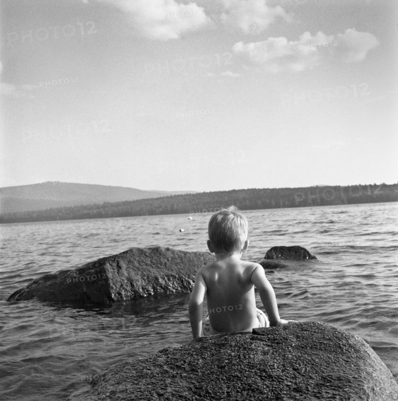 Young Boy Climbing Down a Rock in Lake