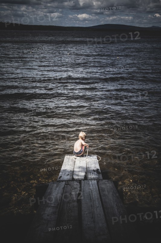 Young boy Playing With Rope at End of Dock on Lake