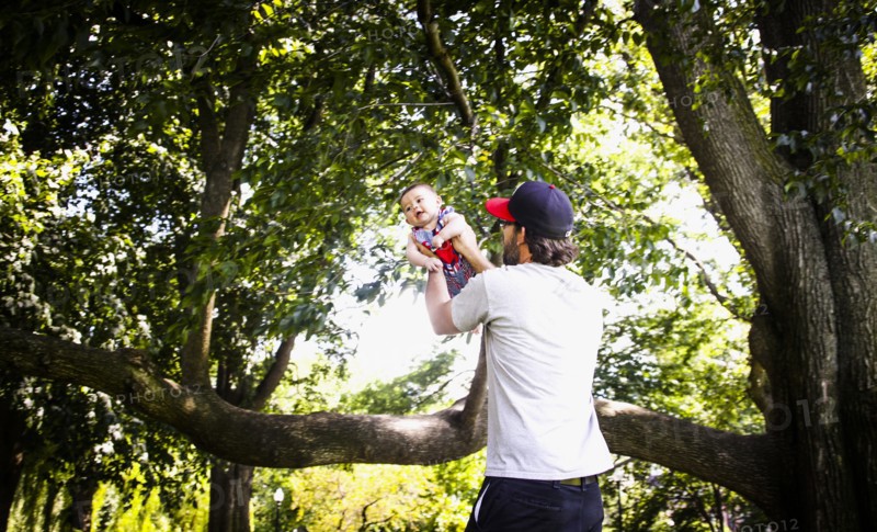 Father Holding up Infant Son in Park