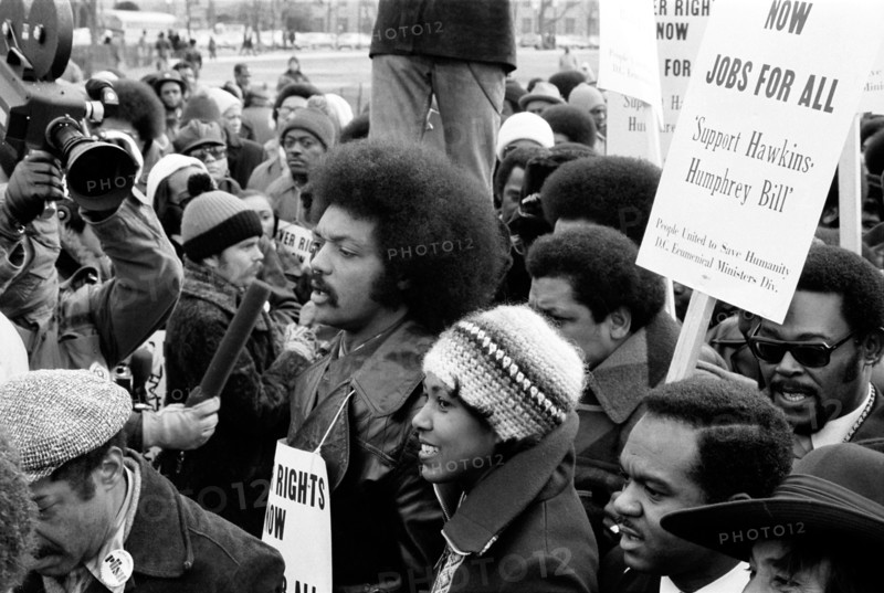 Jesse Jackson speaking into a microphone, surrounded by marchers carrying signs advocating support for the Hawkins-Humphrey Bill for full employment, Washington, D.C., USA, photograph by Thomas J. O'Halloran, January 1975