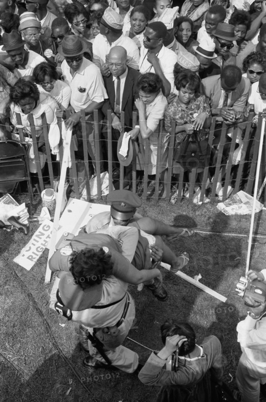 Crowd of African Americans behind a storm fence with police carrying a woman on the other side during March on Washington for Jobs and Freedom, Washington, D.C. USA, photograph by Marion S. Trikosko, August 28, 1963