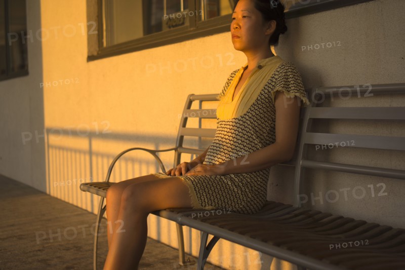 Portrait of Contemplative Mid-Adult Woman sitting on Bench with Shadows