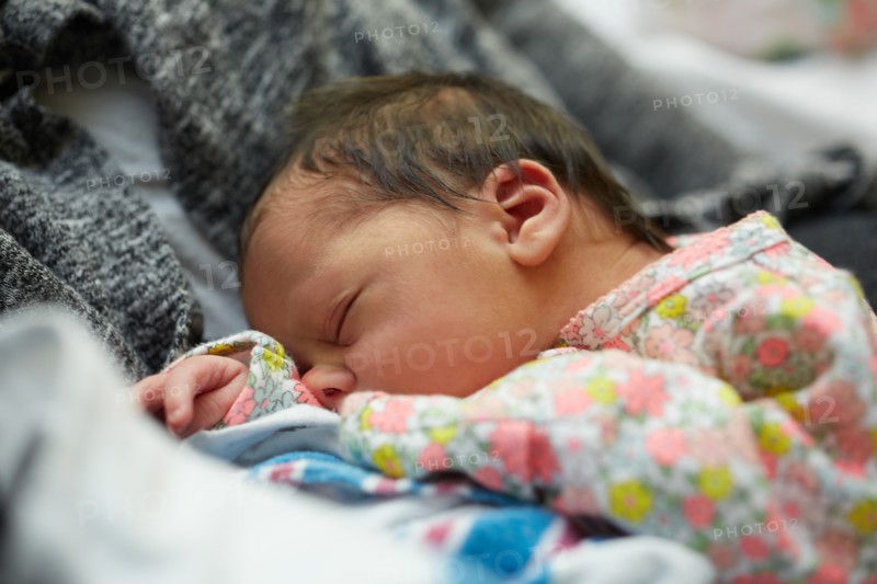 Newborn Baby Girl Sleeping in Mother's Arms in Hospital