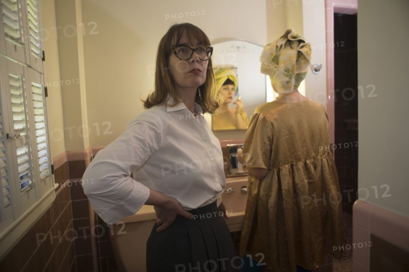 Two Women in Bathroom, One Looking in Mirror
