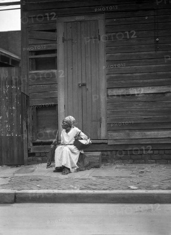 Female Praline Vendor sitting on Steps holding a Basket