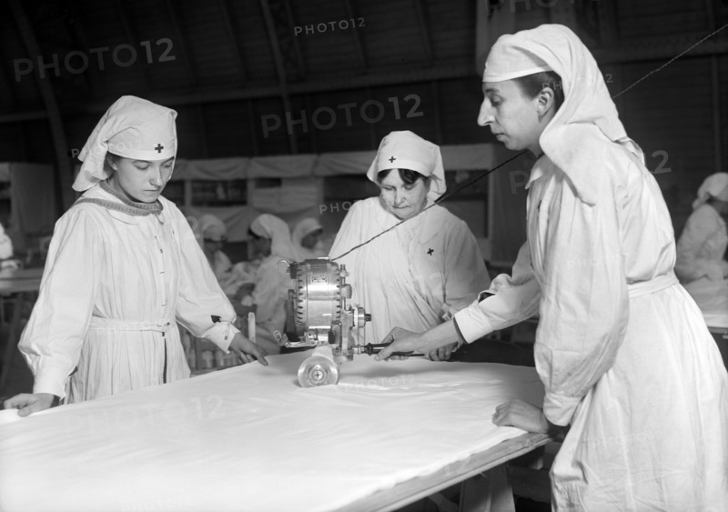 Female American Red Cross Workers cutting Unbleached Muslin for Bias Bandages with Cutting Machine in American Red Cross Workroom for making Surgical Dressings