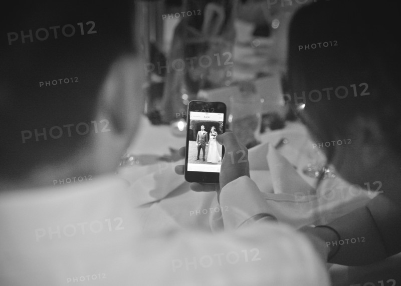 Two People looking at Picture of Wedding Couple on Smart Phone