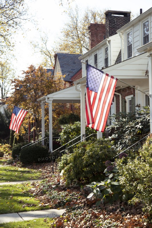 American flags hanging in front of Suburban Houses,