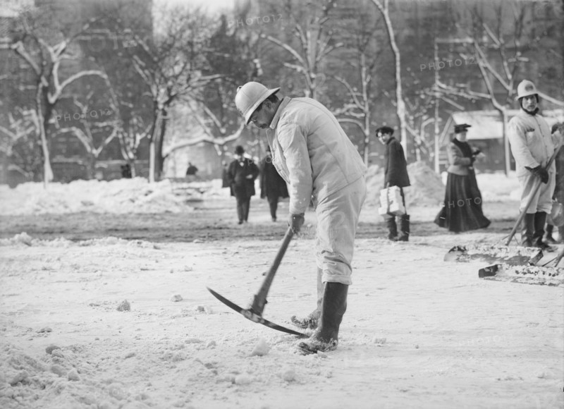Man clearing street with pickaxe after snow storm
