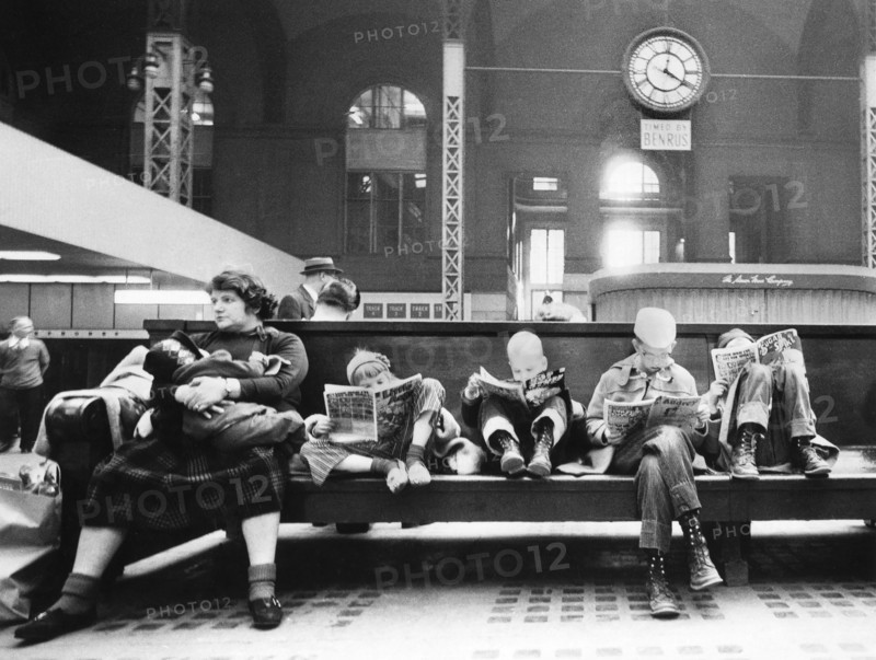 Woman and children seated on bench of train station concourse