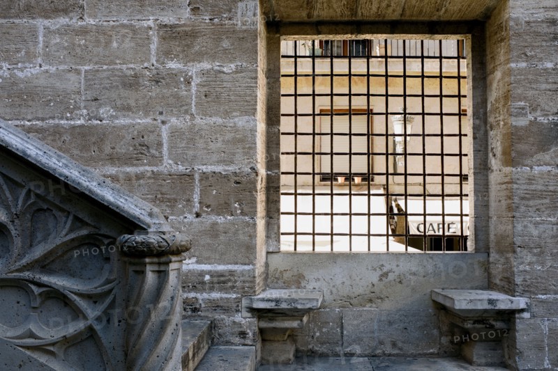 Two Stone Benches beneath Grated Window