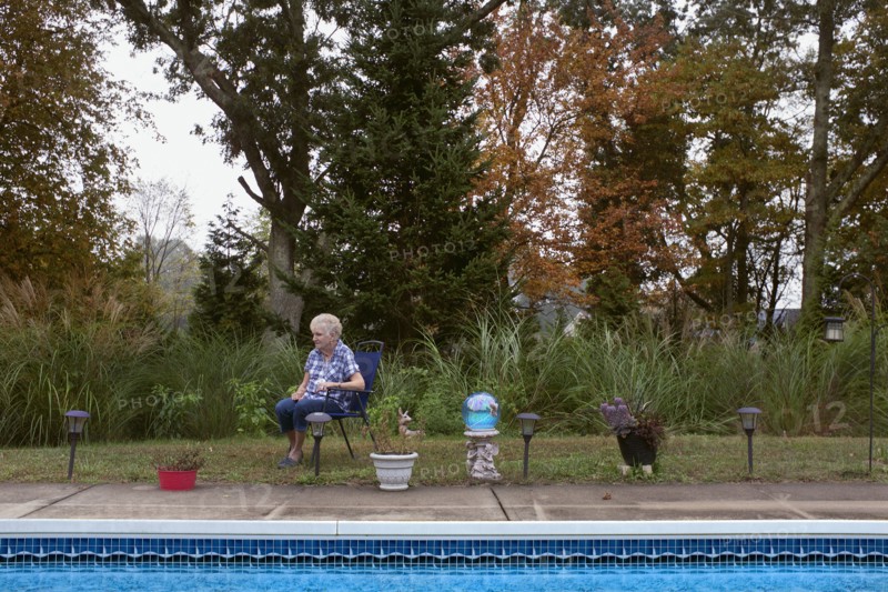 Contemplative Elderly Woman sitting in Chair near Swimming Pool