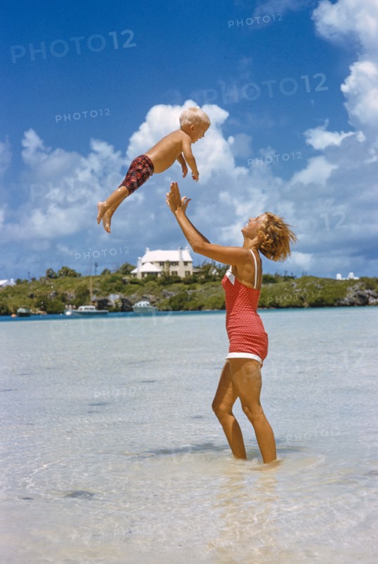 Woman playfully tossing Young Boy in Air at Beach