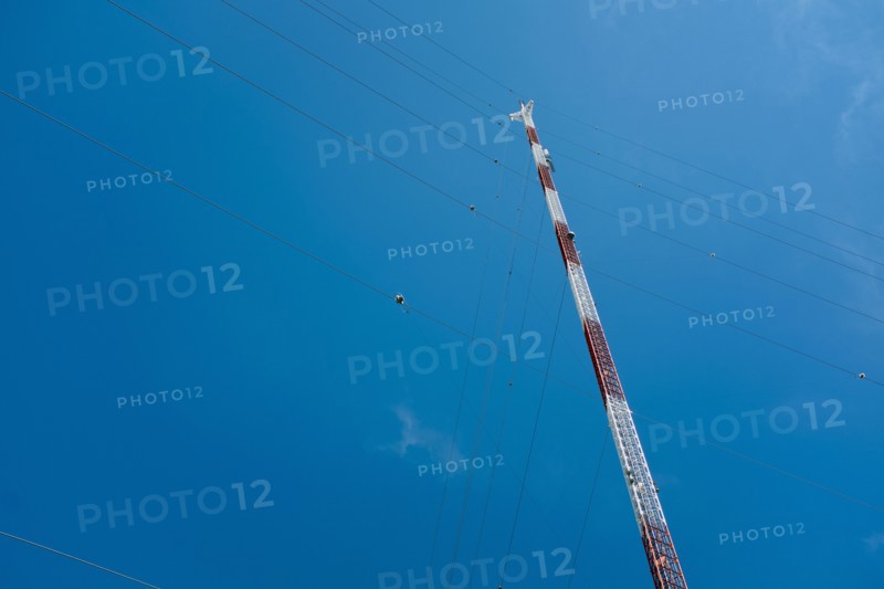 Low Angle View of Communications Tower with Guide Wires against Blue Sky