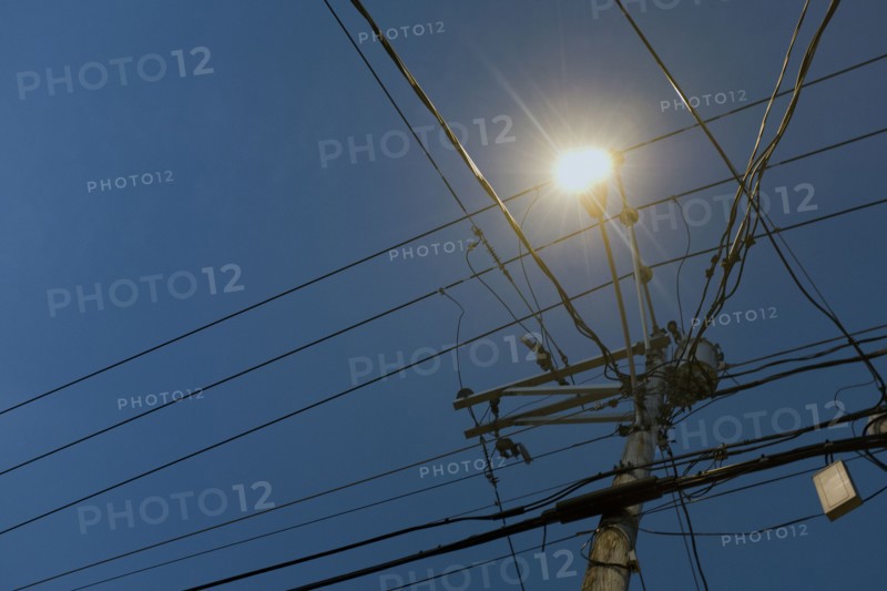 Low Angle View of illuminated Street Light and Utility Wires at Dusk