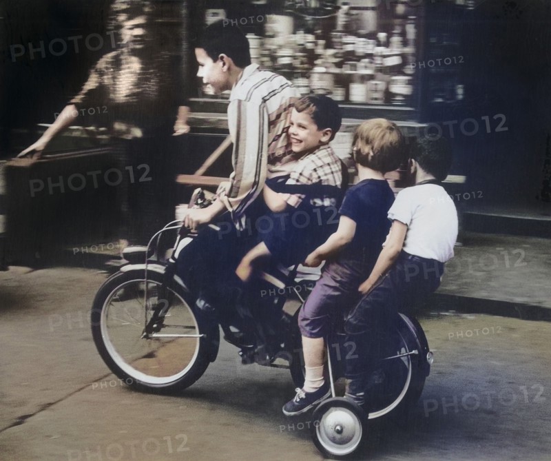 Four Children riding Bicycle on Sidewalk