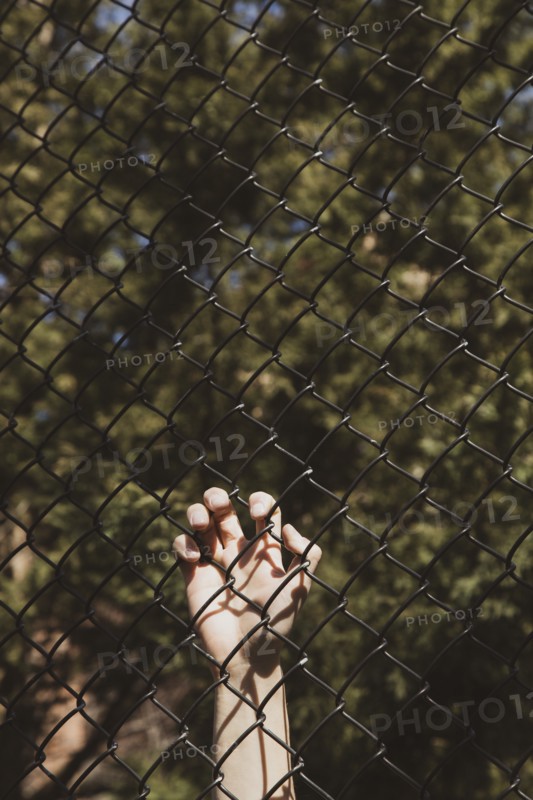 Hand holding black chain link fence at Anti-Asian Violence Rally