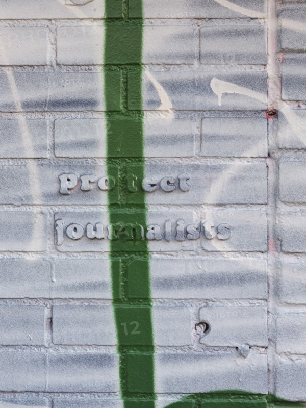 Protect Journalists quote on brick wall covered in paint and graffiti