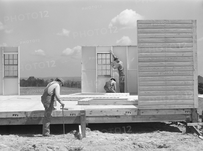Construction workers building prefabricated houses for tenant farmers being relocated due to construction of Camp Croft