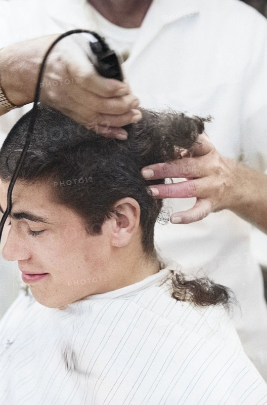 Young U.S. soldier who had just been drafted into U.S. Army getting head shaved by barber