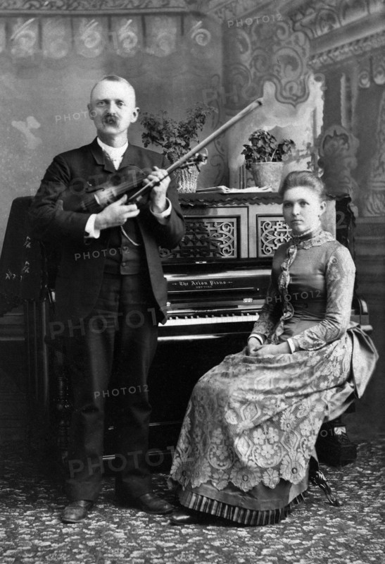 Portrait of Man holding Violin and Woman seated at Piano