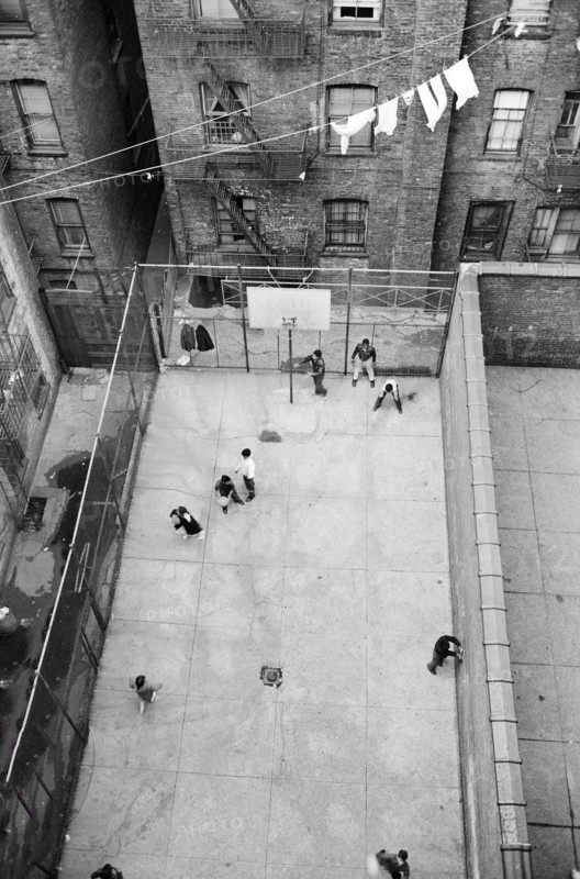 High angle view of Puerto Rican children playing basketball in courtyard surrounded by  buildings