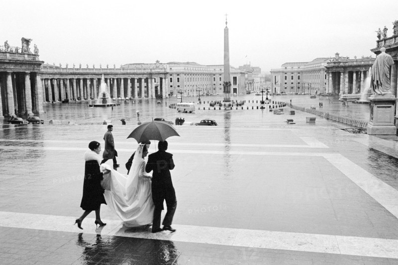 Bride and others crossing St. Peter's Square in the rain