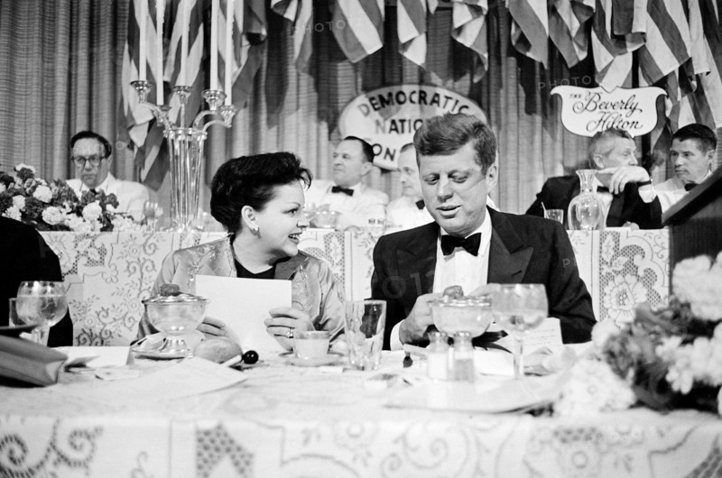 Actress Judy Garland seated next to U.S. Senator John F. Kennedy at dinner
