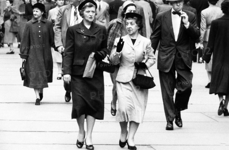 Two women talking while walking on sidewalk