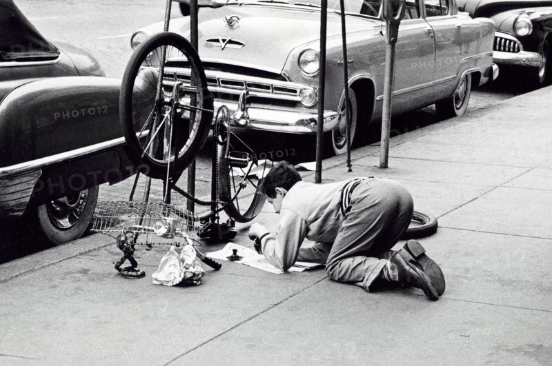 Man fixing bicycle on sidewalk