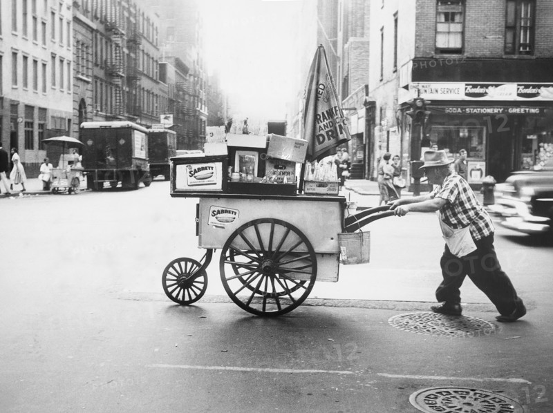 Man pushing hot dog cart across street