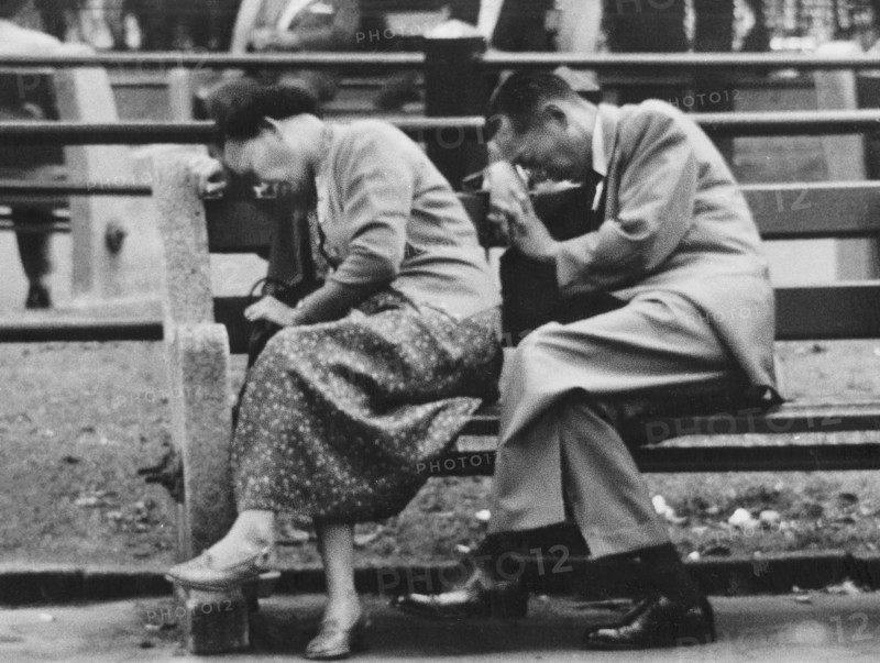 Woman and man napping on park bench