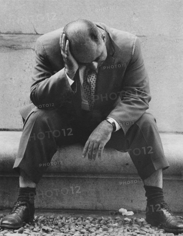 Man sitting with head resting on hand