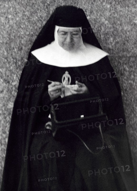 Nun sitting and knitting with purse open on lap