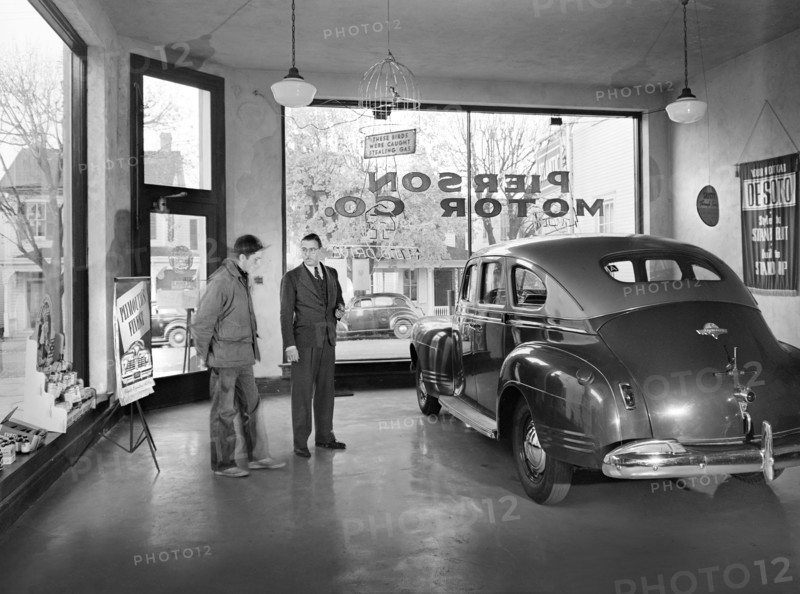 Pierson Motor Company showroom owned by Al Pierson (right) who is showing his one second-hand car to local farmer. Before World War II there always were three brand new cars in his showroom, now during the war, the chief business is repairing, Lititz, Pennsylvania, USA, Marjory Collins, U.S. Office of War Information, November 1942