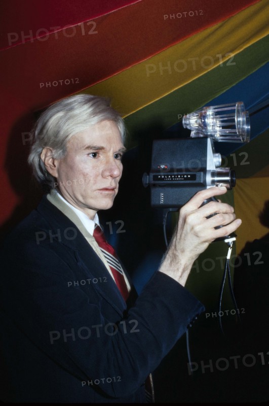 American pop artist Andy Warhol, half-length portrait holding Polaroid Polavision camera, Bernard Gotfryd, 1977