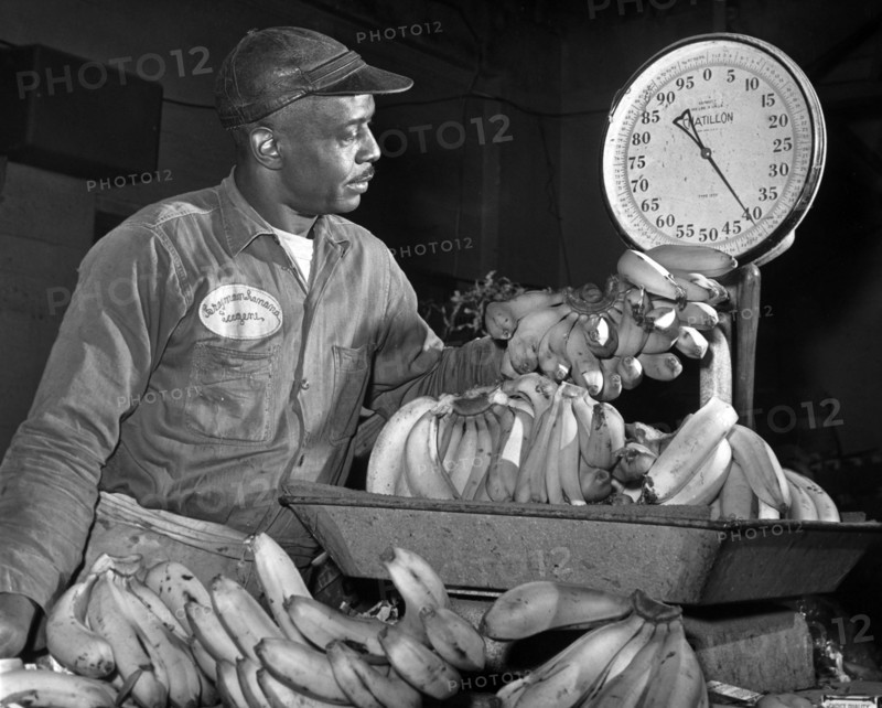 Eugene Smallwood, an employee at Curatolo Banana Corp. weighing bananas, New York City, New York, USA, Dick De Marsico, New York World-Telegram and the Sun Newspaper Photograph Collection, 1962