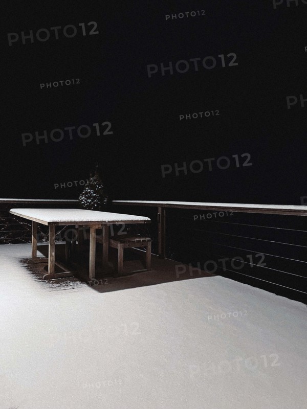 Snow-covered wood table and patio at night