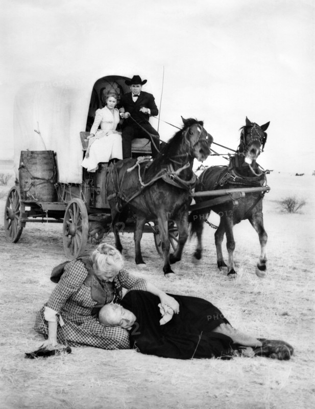 Maria Schell, Glenn Ford (both riding in covered wagon), Aline McMahon, Robert Keith (both on ground), on-set of the western film, "Cimarron", MGM, 1960