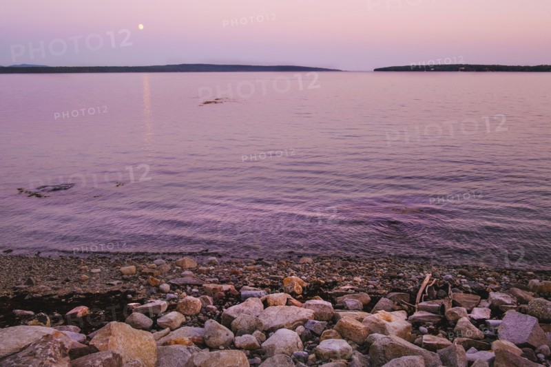 Moonrise at dusk over harbor