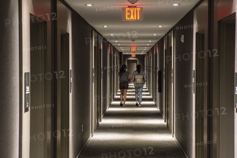 Rear view of two people walking down hotel hallway, diminishing perspective